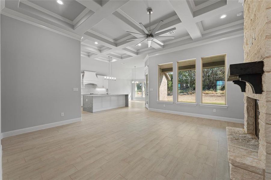 Unfurnished living room with coffered ceiling, crown molding, a fireplace, light hardwood / wood-style floors, and ceiling fan