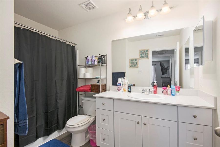 Bathroom with a shower with curtain, vanity, toilet, and hardwood / wood-style flooring