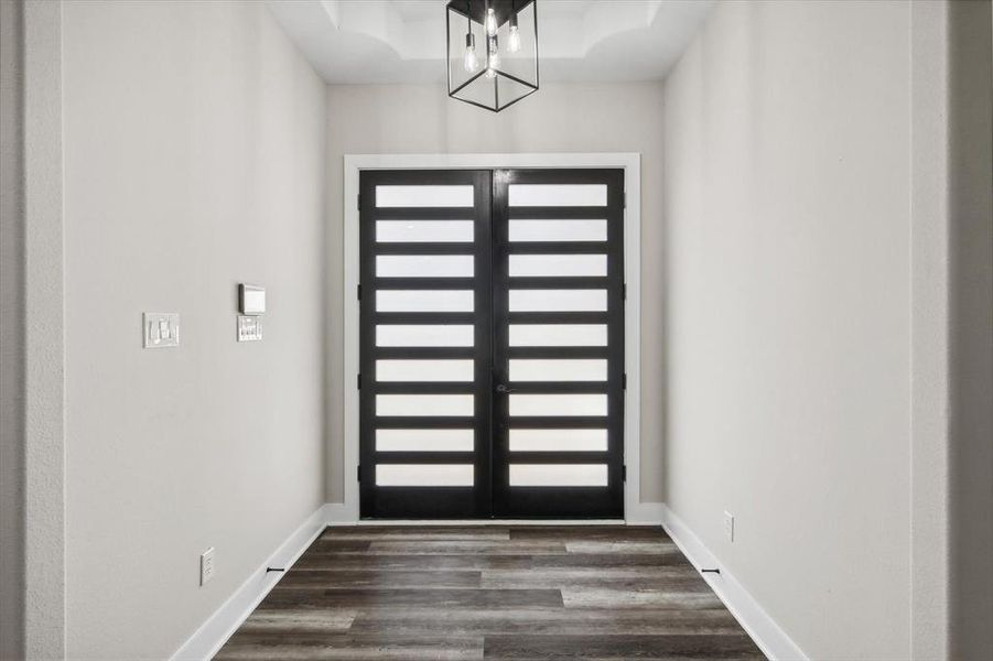 Entryway featuring french doors, dark wood-type flooring, and an inviting chandelier