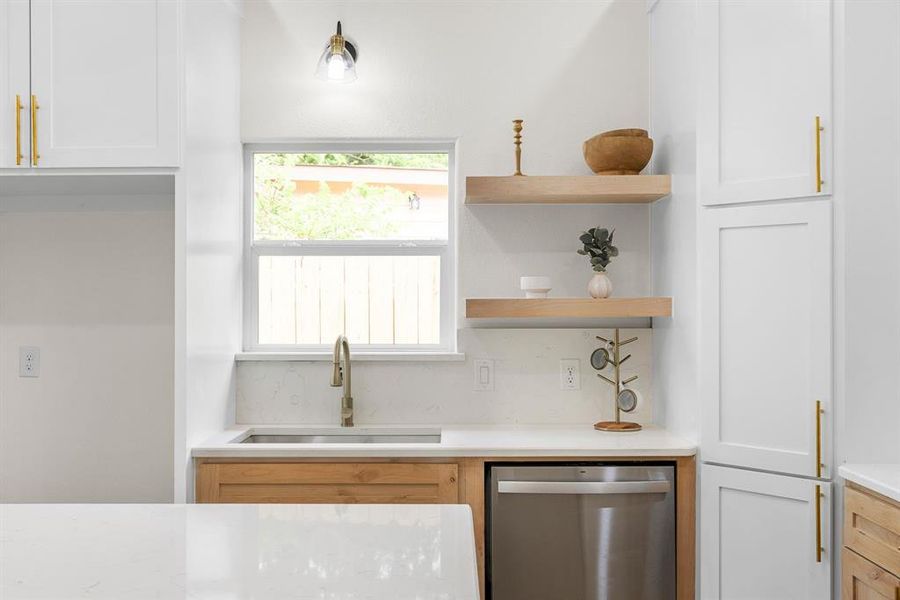 Kitchen featuring decorative backsplash, sink, dishwasher, and white cabinets