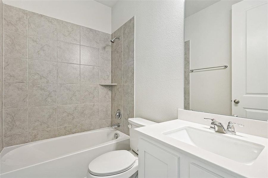 Full bathroom with tiled shower / bath combo, vanity, and toilet