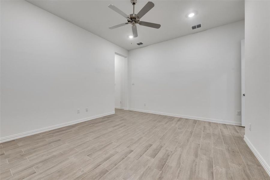 Empty room with ceiling fan and light hardwood / wood-style flooring