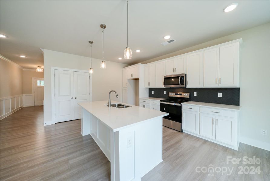 Kitchen features quartz countertops, upgraded appliances, backsplash, faucet, and lighting packages