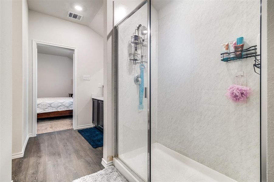 Bathroom featuring vanity, lofted ceiling, wood-type flooring, and a shower with shower door