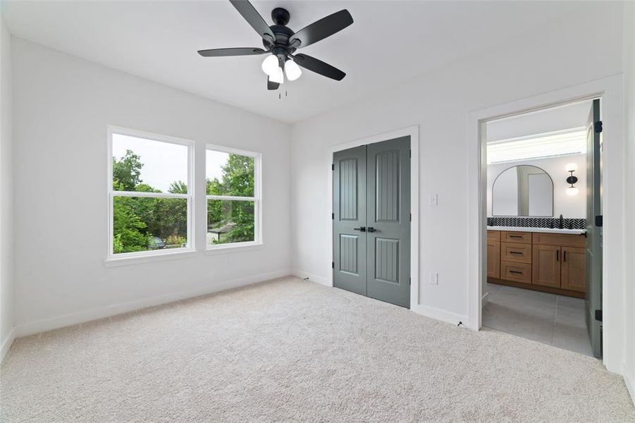 A secondary bedroom with carpet, 2 windows, and an ensuite bathroom provides a cozy and private space for guests or family members. The carpet adds comfort, the window brings in natural light, and the en-suite bathroom offers convenience and privacy