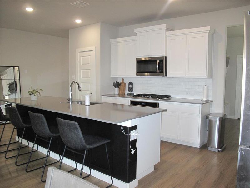 Kitchen featuring an island with sink, white cabinets, appliances with stainless steel finishes, and sink