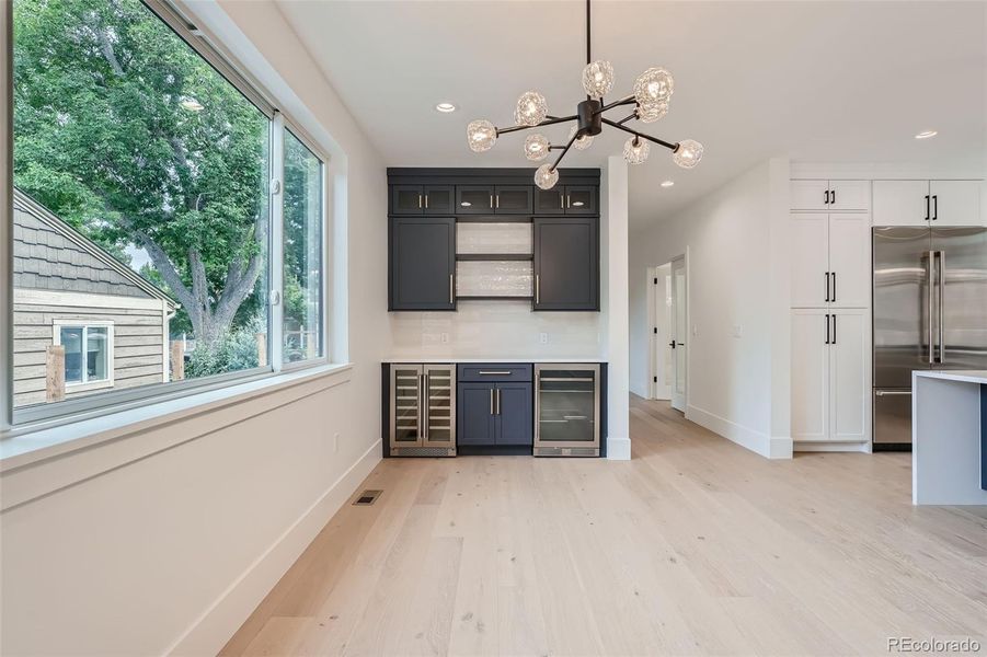 Bright, airy dining area has built-ins with wine and beverage fridges.