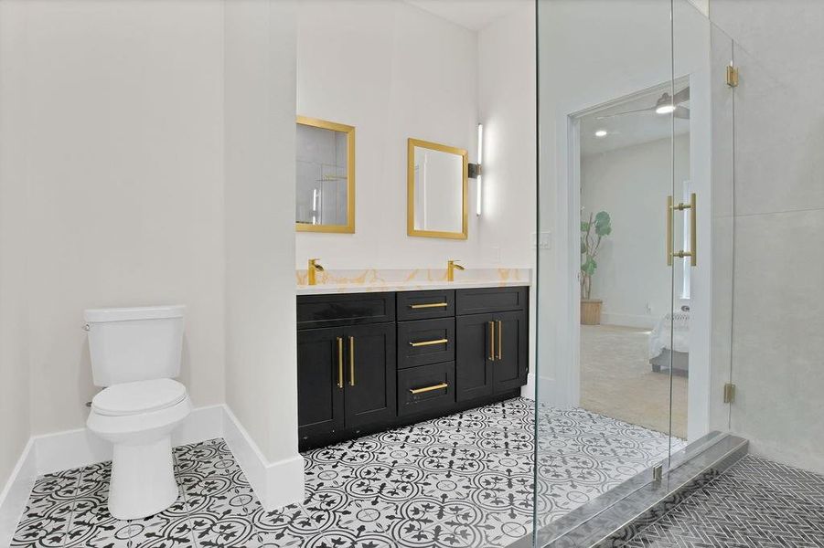 Bathroom with vanity, toilet, walk in shower, and tile patterned flooring