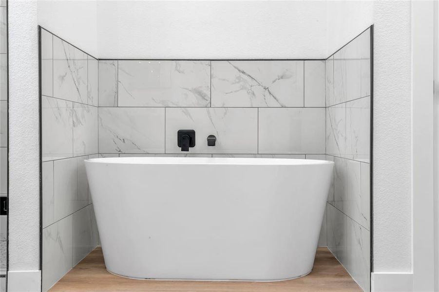 Bathroom with a bath, tile walls, and hardwood / wood-style flooring