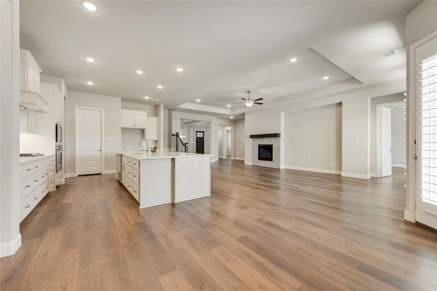 Kitchen with light hardwood / wood-style flooring, white cabinets, and a kitchen island with sink