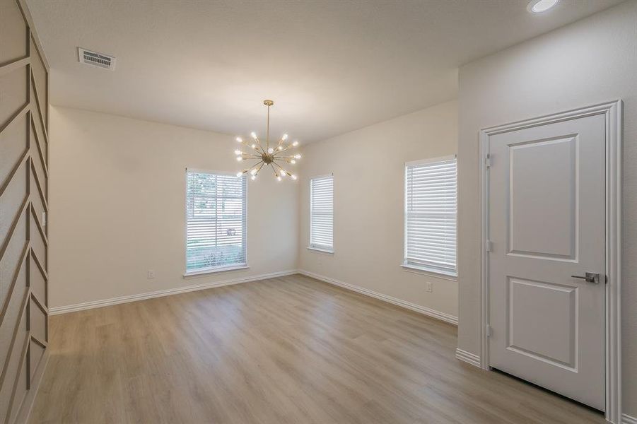 Empty room featuring a chandelier and light hardwood / wood-style floors