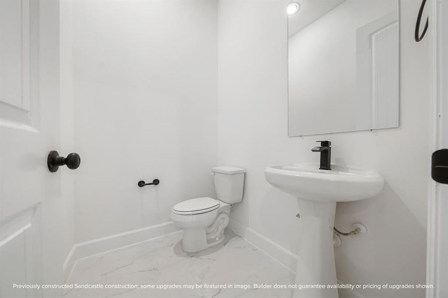 A downstairs retreat featuring a timeless pedestal sink, offering both style and convenience.