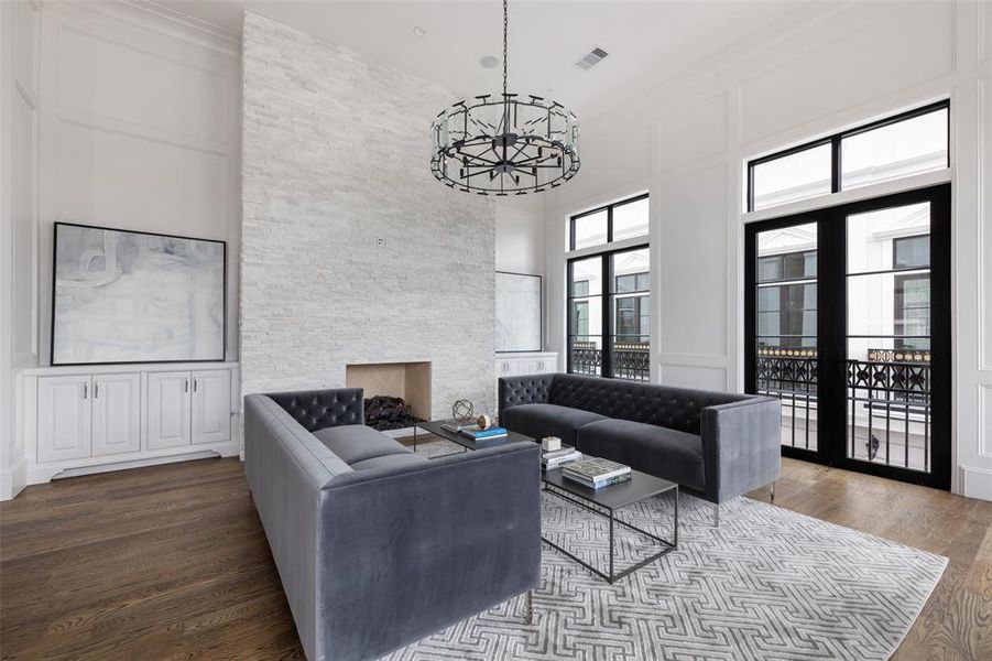 The whole of the expansive living area is lined with a triplicate of French doors which open to the expansive Juliet balcony with iron detailing. Transom windows above the French doors and statement overhead lighting further illuminate the space. Image from previously completed home in the community.