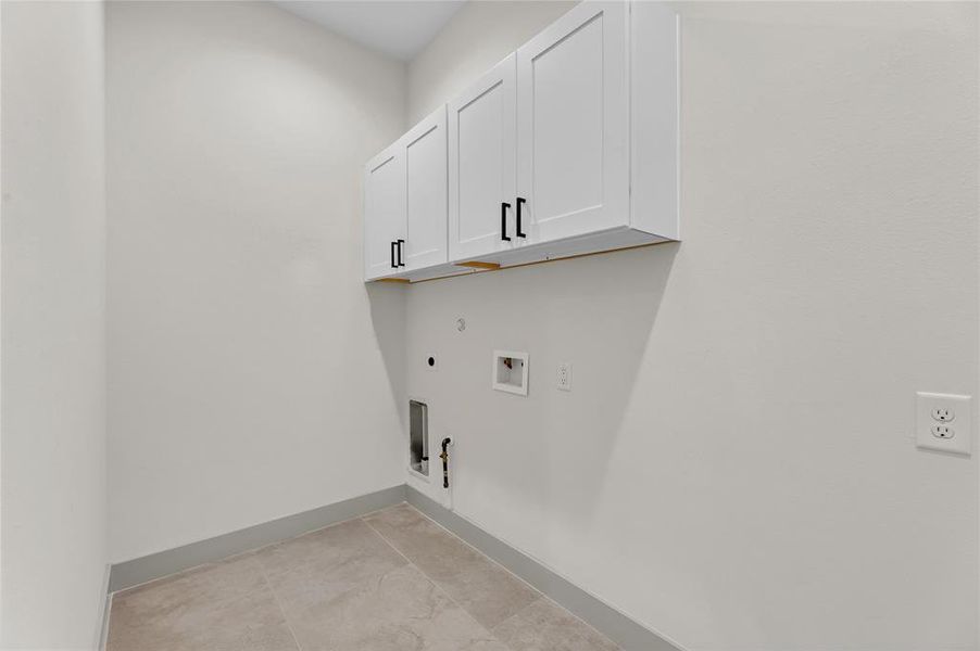 Nice size laundry room with white cabinets, tiled floor on 1st floor