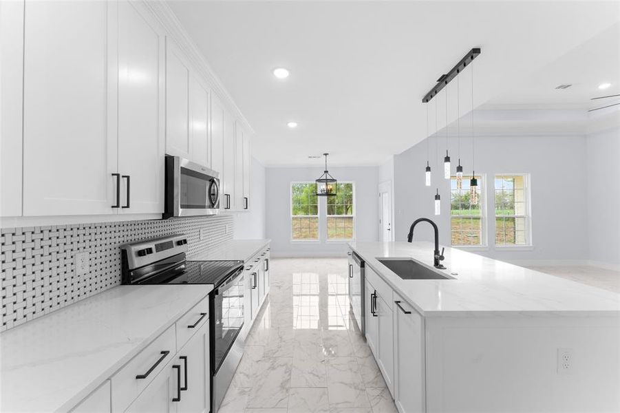 Kitchen with stainless steel appliances, white cabinetry, and sink