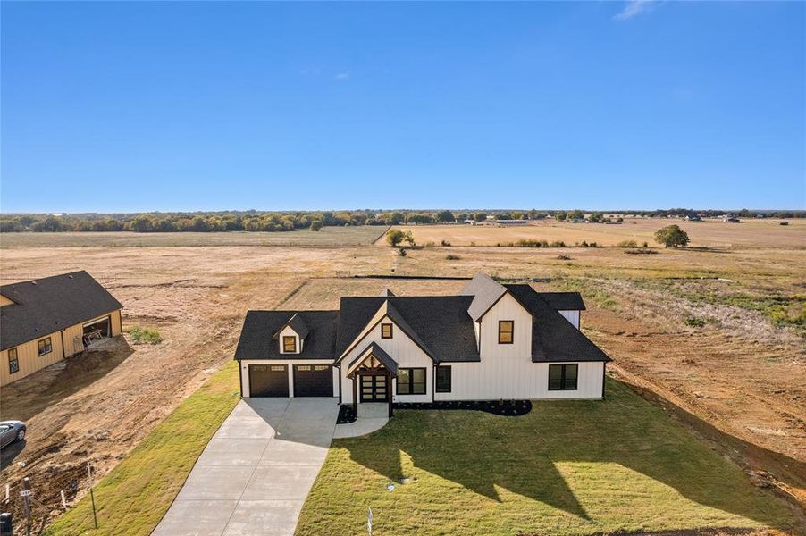 View of front of house with a front lawn, a garage, and a rural view