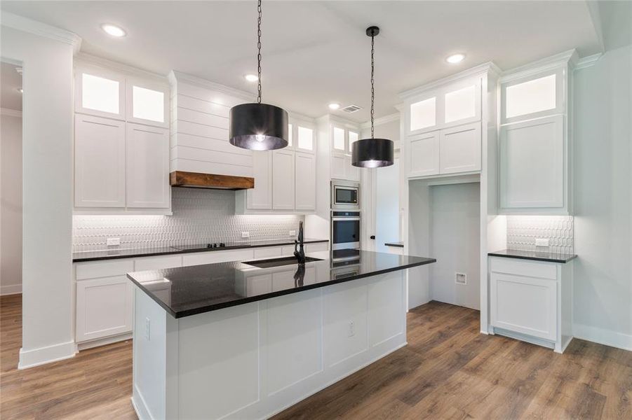 Kitchen featuring white cabinets, an island with sink, dark hardwood / wood-style floors, appliances with stainless steel finishes, and sink