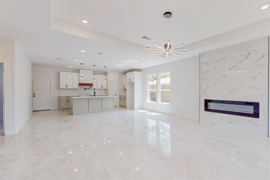 Unfurnished living room featuring sink, light tile patterned floors, and an inviting chandelier