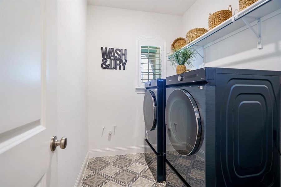 Clothes washing area with light tile patterned floors and separate washer and dryer