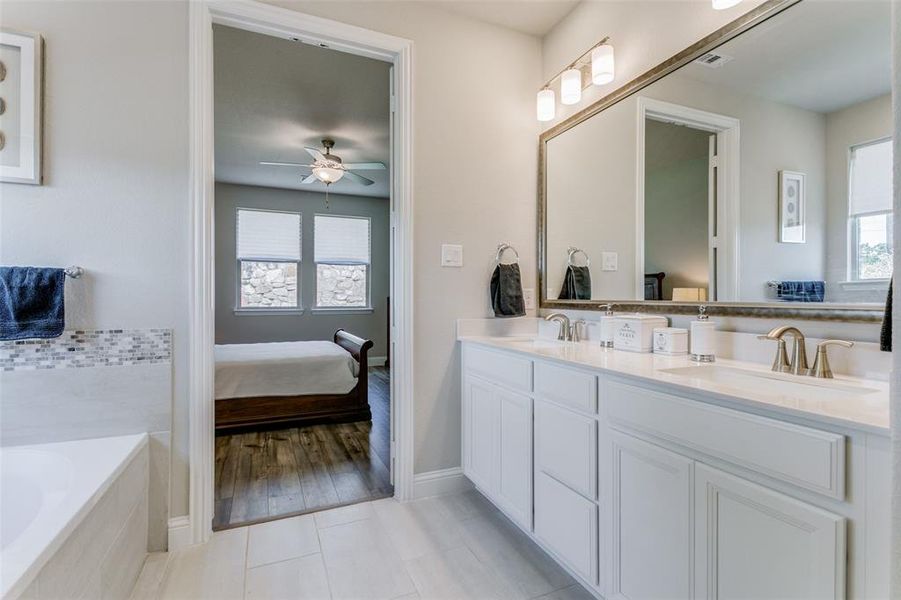 Bathroom featuring dual bowl vanity, tiled bath, ceiling fan, and wood-type flooring