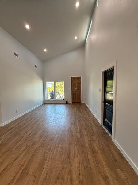 Spare room with hardwood / wood-style flooring and high vaulted ceiling