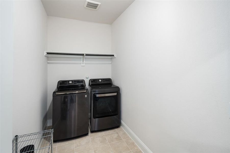 Clothes washing area featuring light tile patterned floors and washer and dryer