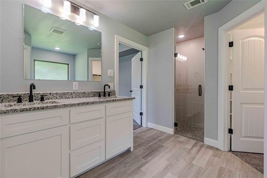 Bathroom with walk in shower, vanity with extensive cabinet space, wood-type flooring, and double sink