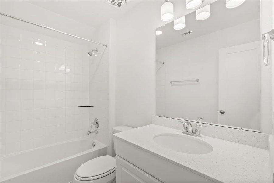 The secondary bath features tile flooring, white cabinetry and light countertops and a shower/tub combo. Perfect for accommodating any visiting family and friends.