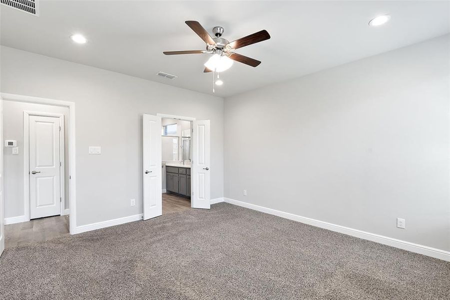 Unfurnished bedroom with ensuite bathroom, carpet floors, and ceiling fan