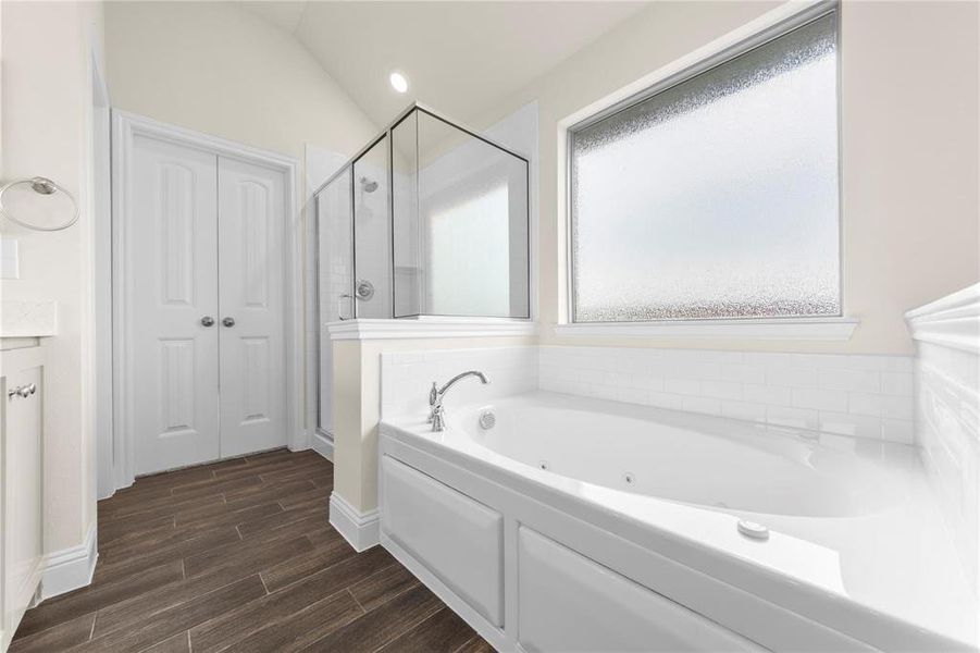 Bathroom featuring vaulted ceiling, wood-type flooring, and shower with separate bathtub