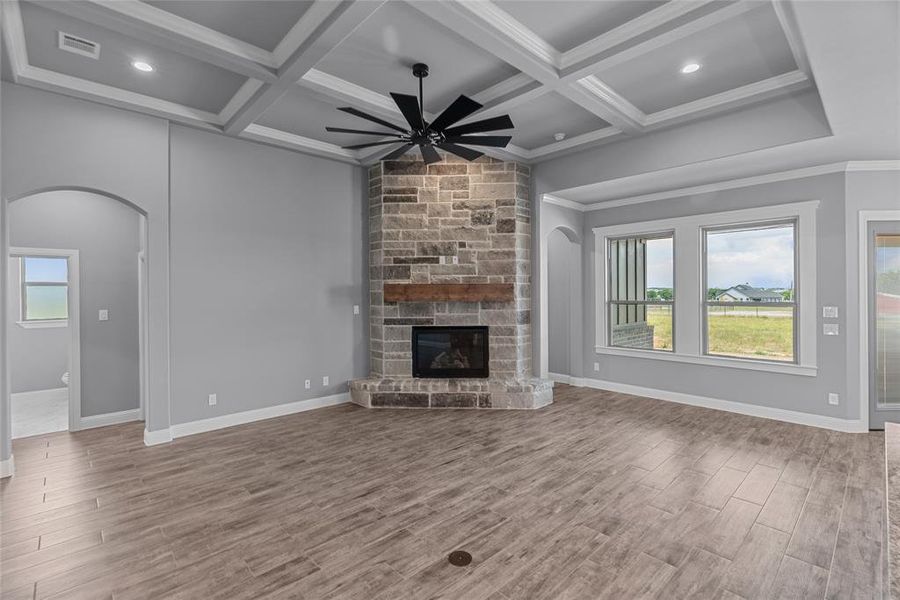 Unfurnished living room featuring hardwood / wood-style flooring, coffered ceiling, a fireplace, and ceiling fan