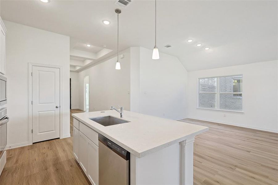 Kitchen with dishwasher, white cabinetry, hanging light fixtures, and sink