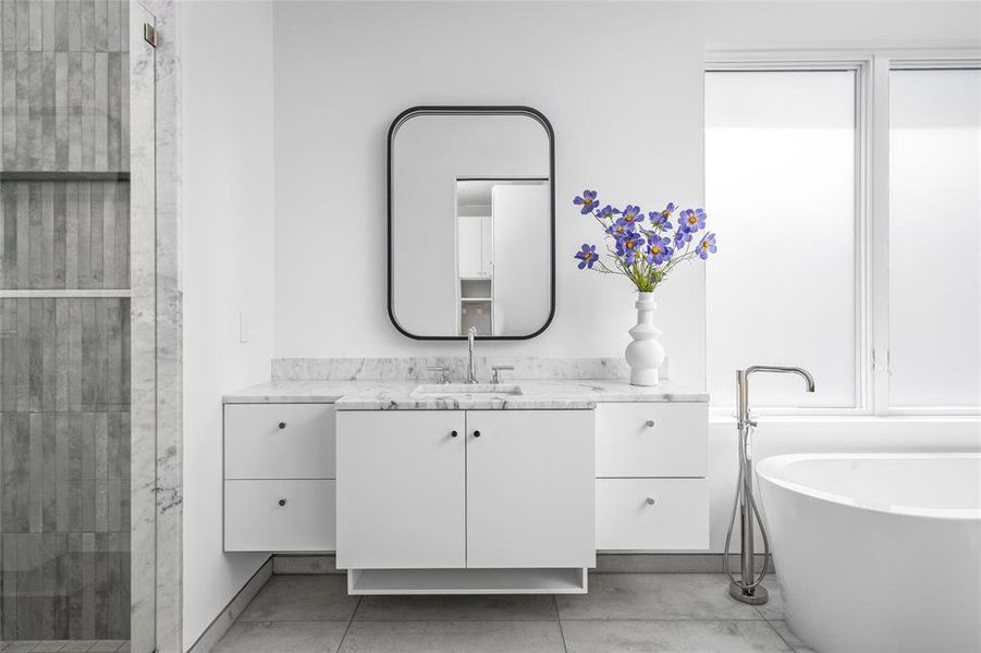 The sleek black-trim, front-lit mirrors over the dual vanities add a modern contrast, perfectly complementing the overall design of this serene and spa-like space.