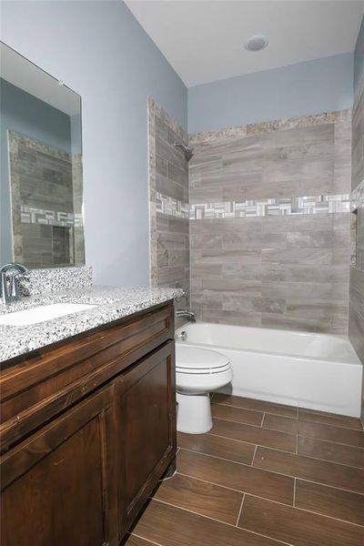 Full bathroom featuring tiled shower / bath combo, vanity, and toilet