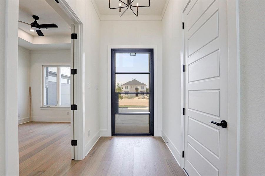 Doorway to outside with ceiling fan with notable chandelier and light wood-type flooring