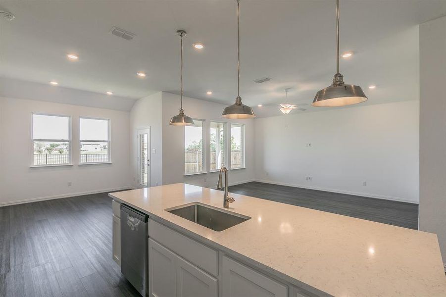 Kitchen featuring dishwasher, light stone countertops, sink, and a wealth of natural light