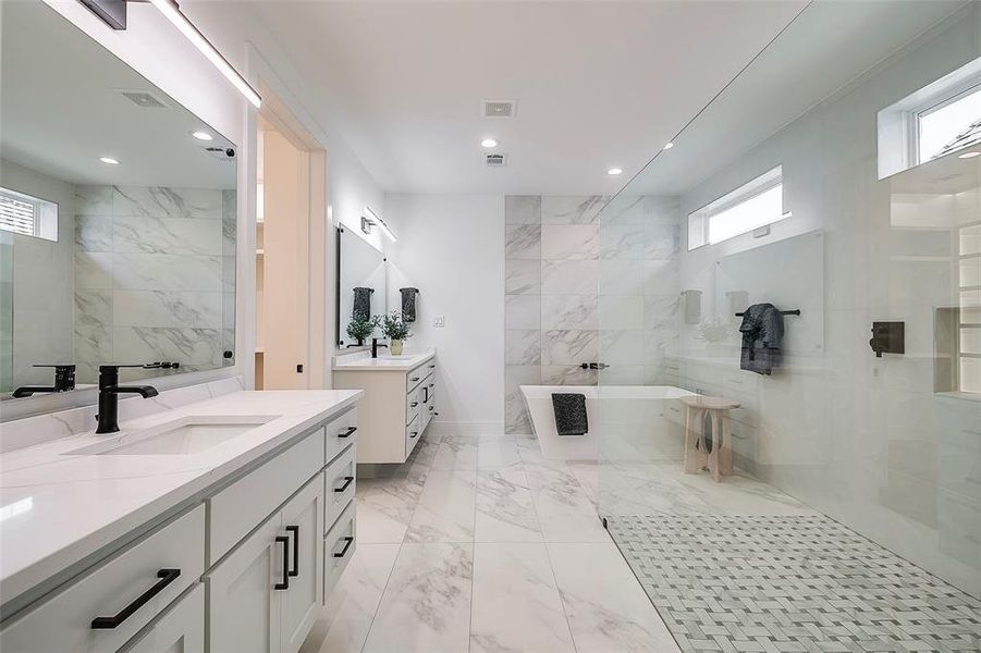 Bathroom featuring a bath, vanity, and plenty of natural light