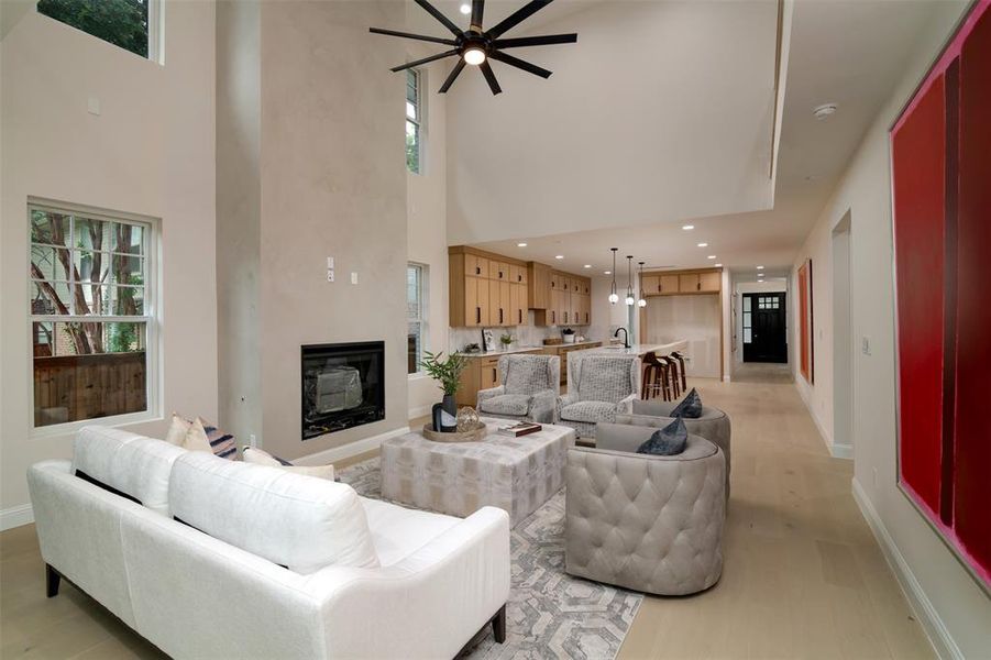 Living room with a towering ceiling, light wood-type flooring, sink, and ceiling fan