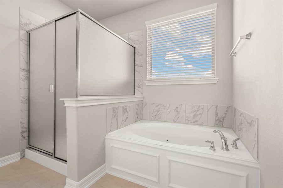 This additional view of your primary bathroom features tile flooring, fresh paint, walk-in shower, a separate garden tub, and a large walk-in closet.