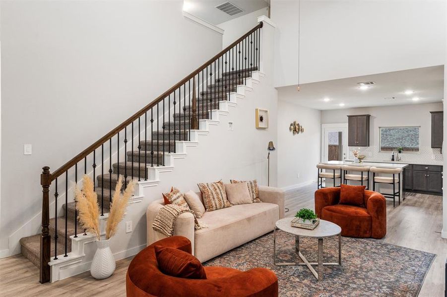 Living room featuring sink, light hardwood / wood-style flooring, and a high ceiling