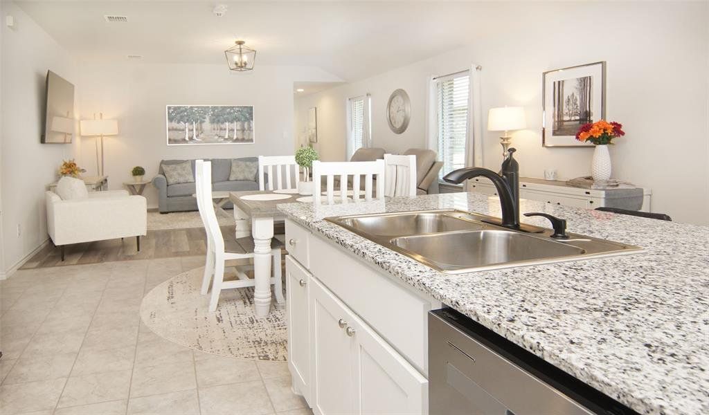 Kitchen featuring dishwasher, sink, light tile patterned floors, white cabinetry, and light stone counters