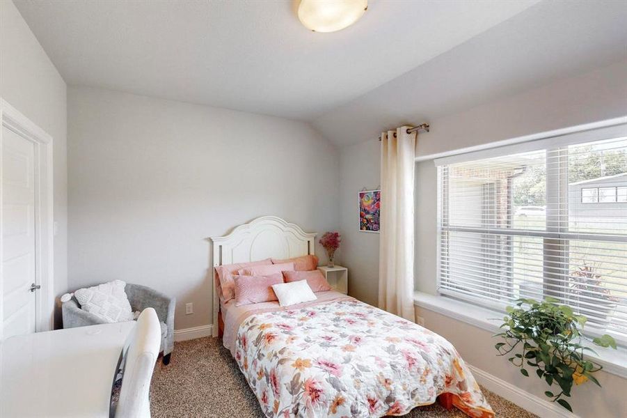 Bedroom with lofted ceiling and light colored carpet