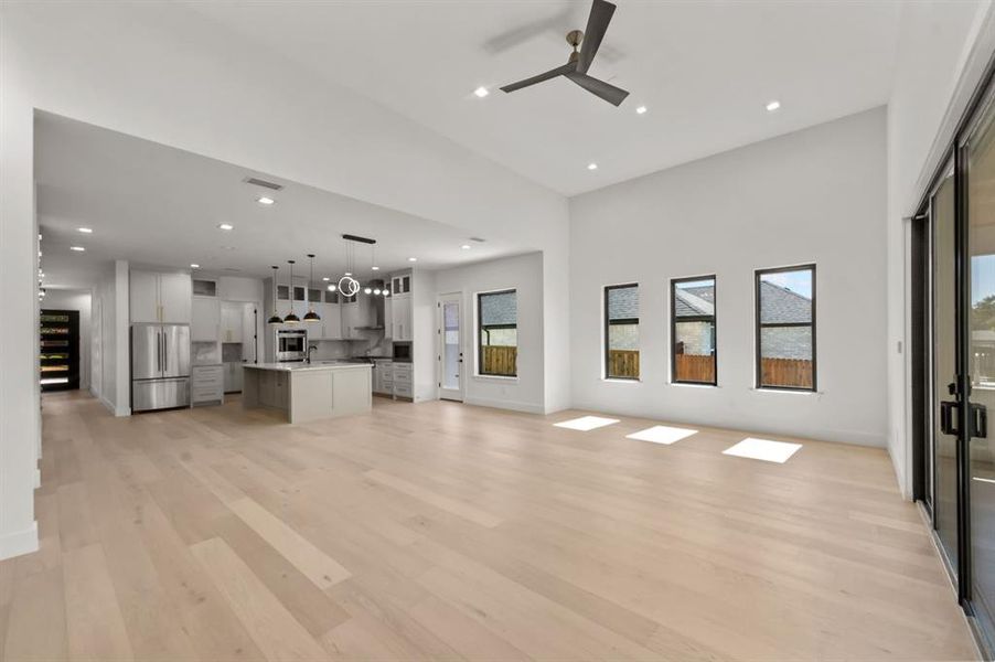 Living room featuring ceiling fan, light wood-type flooring, and a high ceiling