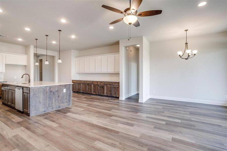 Kitchen with light hardwood / wood-style floors, white cabinetry, ceiling fan with notable chandelier, decorative light fixtures, and a large island