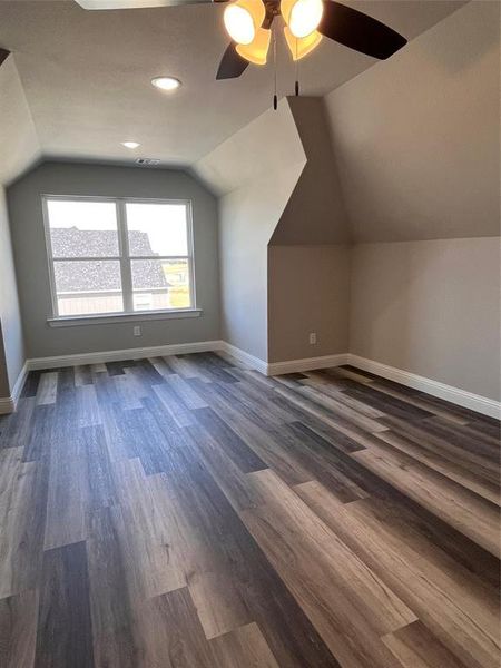 Bonus room featuring ceiling fan, vaulted ceiling, and dark wood-type flooring