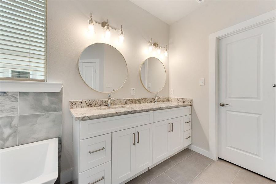 Bathroom with vanity, a bathtub, and tile patterned flooring