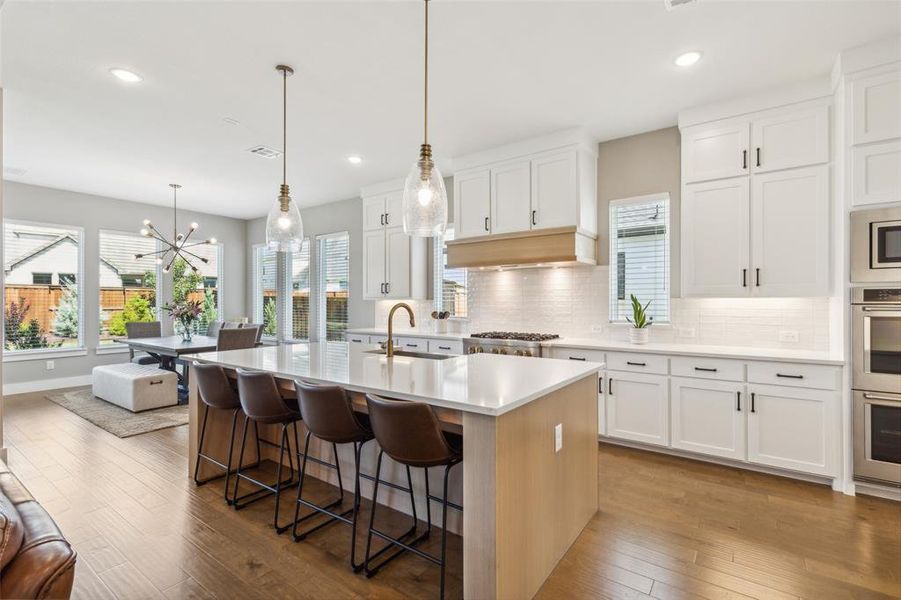 Kitchen featuring white cabinetry, sink, a center island with sink, and hardwood / wood-style floors