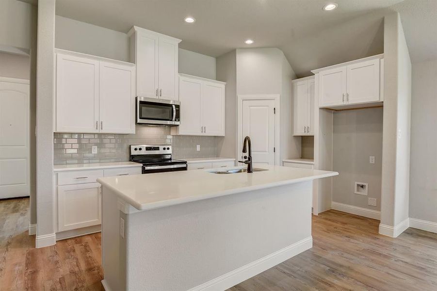 Kitchen featuring a kitchen island with sink, lofted ceiling, light wood-type flooring, and appliances with stainless steel finishes