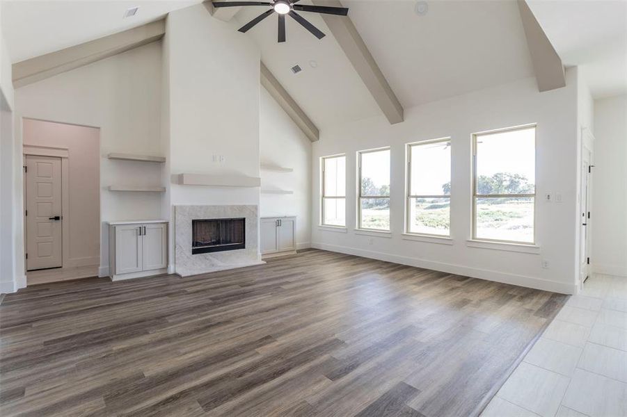 Unfurnished living room with high vaulted ceiling, a high end fireplace, ceiling fan, and hardwood / wood-style flooring