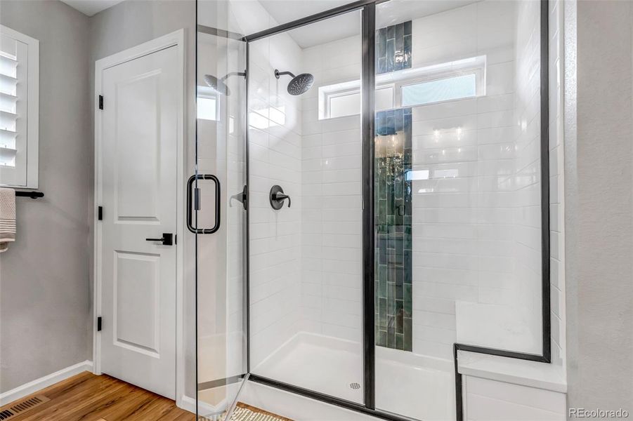 Primary walk-in shower with glass door and upgraded chevron tile